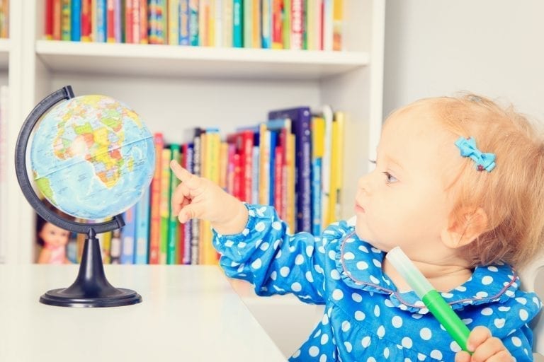 little girl pointing to a globe