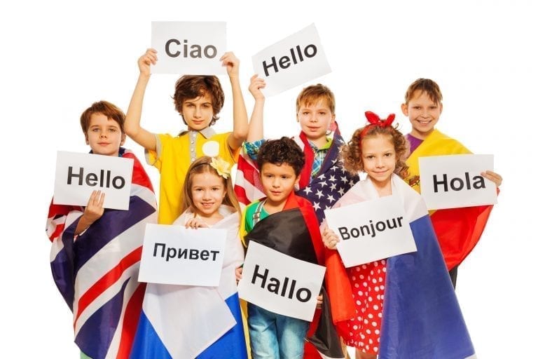 Kids wrapped in flags of USA and European nations, holding greeting signs in different languages, isolated on white