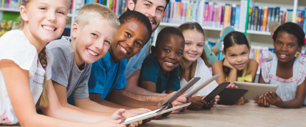 Teacher and kids lying on floor using digital tablet in library 788593